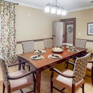 A well-decorated dining room with a wooden table set for six, featuring elegant chairs and warm lighting.