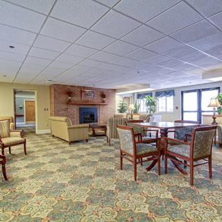 A cozy lounge area featuring comfortable seating, a fireplace, and natural light from large windows.