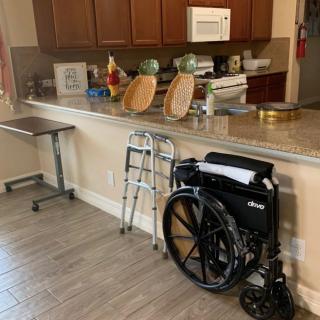 A kitchen with mobility aids including a wheelchair and a walker by the countertop.