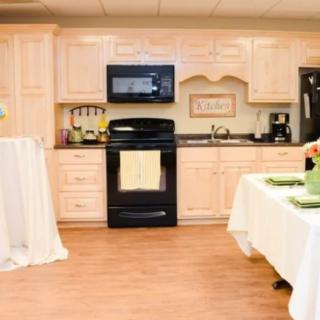 A modern kitchen with light wood cabinets, a black oven and microwave, and neatly arranged countertops.