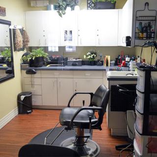 A cozy hair salon with a styling chair, mirror, and various hairdressing equipment.