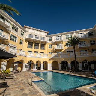 A sunny day by the poolside of a charming apartment complex adorned with palm trees.