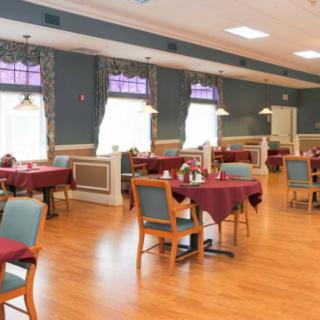 An empty dining room with neatly arranged tables and chairs on a wooden floor.