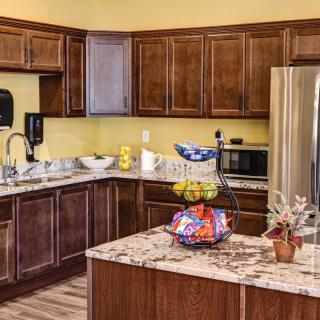 Modern kitchen with wooden cabinets, a central island, and stainless steel appliances.