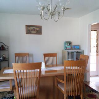 A cozy dining room with a wooden table and chairs, illuminated by an elegant chandelier.