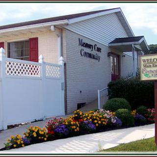 A nursing care building with a well-maintained garden and colorful flowers next to a welcoming sign.