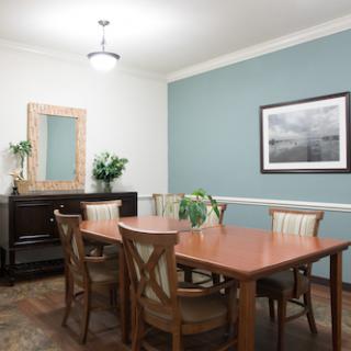 A spacious dining area featuring a wooden table and chairs, complemented by decorative elements such as a mirror and artwork.
