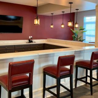 A modern bar area with red stools and pendant lighting.