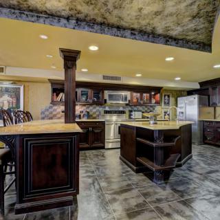 A modern kitchen with a large island and elegant cabinetry, featuring sleek appliances and ample lighting.