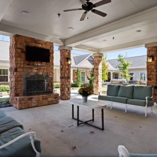 A cozy outdoor patio with a fireplace, TV, and comfortable seating.