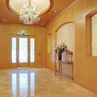 A luxurious lobby featuring a grand chandelier and a marble floor, with floral decorations enhancing the elegant entrance.
