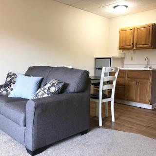 A cozy living space featuring a comfortable sofa and a kitchenette.