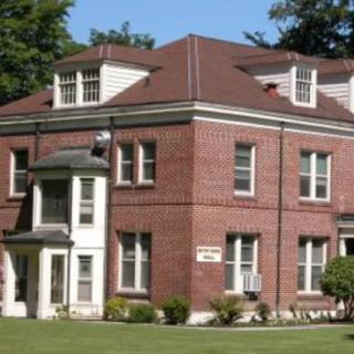A historic brick building with a well-maintained lawn.