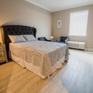 A modern and cozy bedroom with a bed, chairs, and a window.