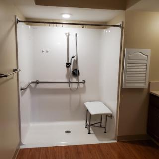 An accessible shower space featuring a bench and grab bars for safety.