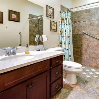 A well-organized bathroom with a wooden vanity, large mirror, and floral shower curtain.