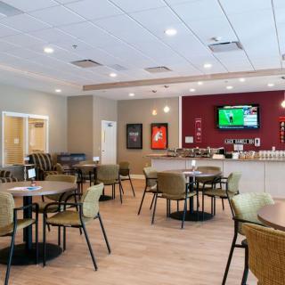 A modern cafe interior with several tables and chairs, featuring a TV on the wall.