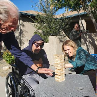 A joyful moment as family members engage in a game of Jenga outdoors.