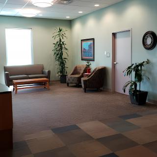 A spacious and well-lit waiting room with chairs, a sofa, and decorative plants.