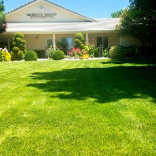 A well-maintained building surrounded by a lush green lawn and colorful garden.