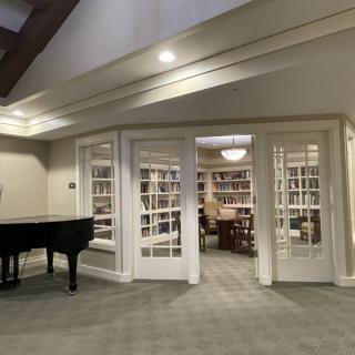 A cozy library with a grand piano and bookshelves.