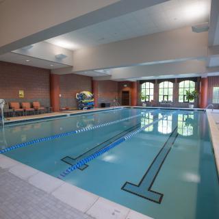 An indoor swimming pool with clean, clear water and comfortable seating areas.