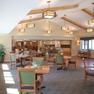 A well-lit dining area with neatly arranged tables and chairs, featuring modern lighting fixtures.