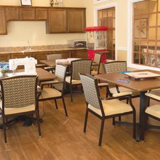 A cozy dining area with several tables and chairs, featuring a popcorn machine and wooden cabinetry.