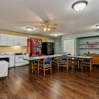 A spacious kitchen and dining area featuring wooden flooring, a vending machine, and ample seating.