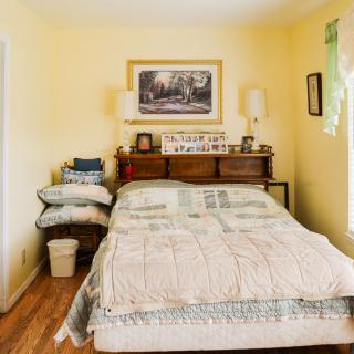 A cozy bedroom with a bed, wooden furniture, and decorative elements on the wall.
