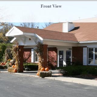 Front view of a building entrance with autumn decorations and pumpkins.