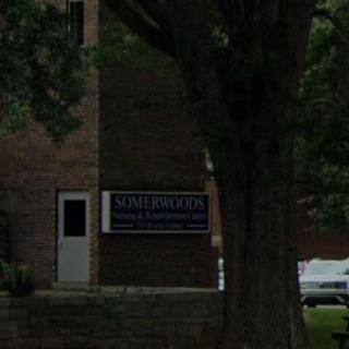 A brick building with a sign and a tree in the foreground.