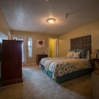 A cozy bedroom with a large bed, dresser, and soft lighting.