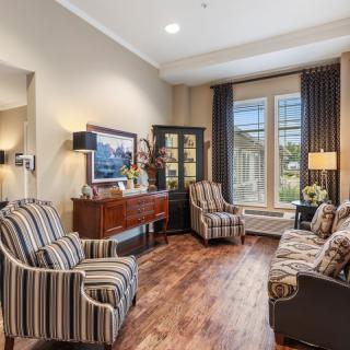 A well-decorated living room with striped chairs, a hardwood floor, and large windows.