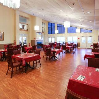 An elegant restaurant dining room with red tablecloths and wooden flooring.