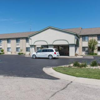 A two-story hotel building with a van parked in front of the entrance.