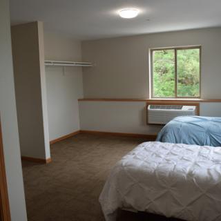 A spacious bedroom featuring two beds and a large window.