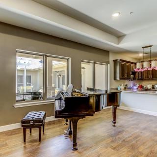 A modern living room featuring a grand piano and ample natural light.