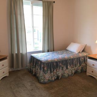 A minimalist bedroom with a single bed, nightstands, and curtains by the window.
