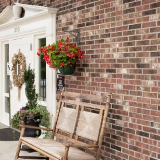 A cozy entrance with a wooden bench, hanging flowers, and a decorative wreath on the door.