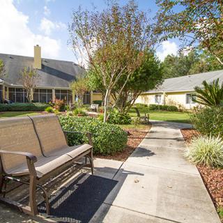 A peaceful garden area with a pathway, benches, and surrounding greenery.