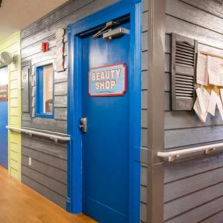 A colorful hallway in a children's hospital with a bright blue door labeled 'Beach Shack'.