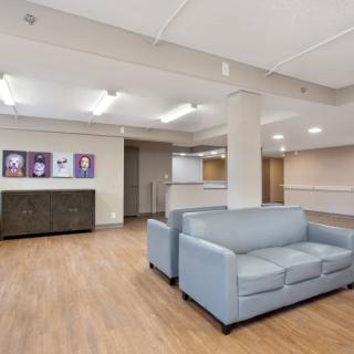 A modern lobby area featuring light gray sofas, wood flooring, and contemporary artwork on the walls.
