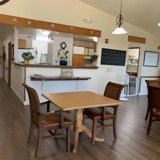 A cozy dining area with wooden tables and chairs, adjacent to a kitchen space.