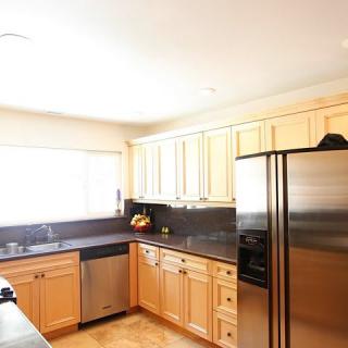 A modern kitchen with stainless steel appliances and light wooden cabinets.