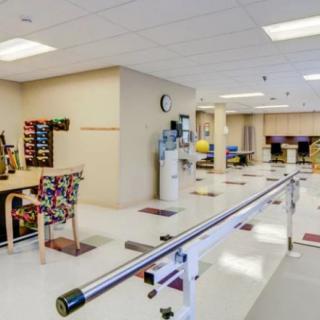 A physical therapy room equipped with parallel bars and various exercise tools.