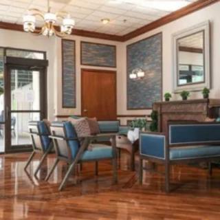 A well-furnished waiting area with blue upholstered chairs and a wooden table.