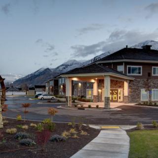 A modern residential building with a mountain backdrop during the evening.