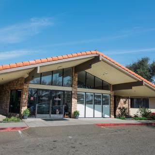 A modern building with a distinct triangular roof design, featuring large glass doors and windows, under a clear blue sky.