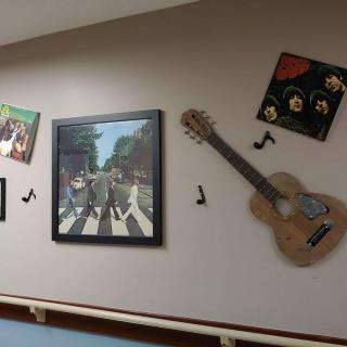 A wall decorated with music-themed artwork, including a guitar, album covers, and musical notes.